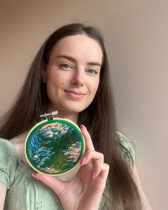 Ira, the artist behind Blooming Day, smiling and holding a small embroidered water-lily hoop